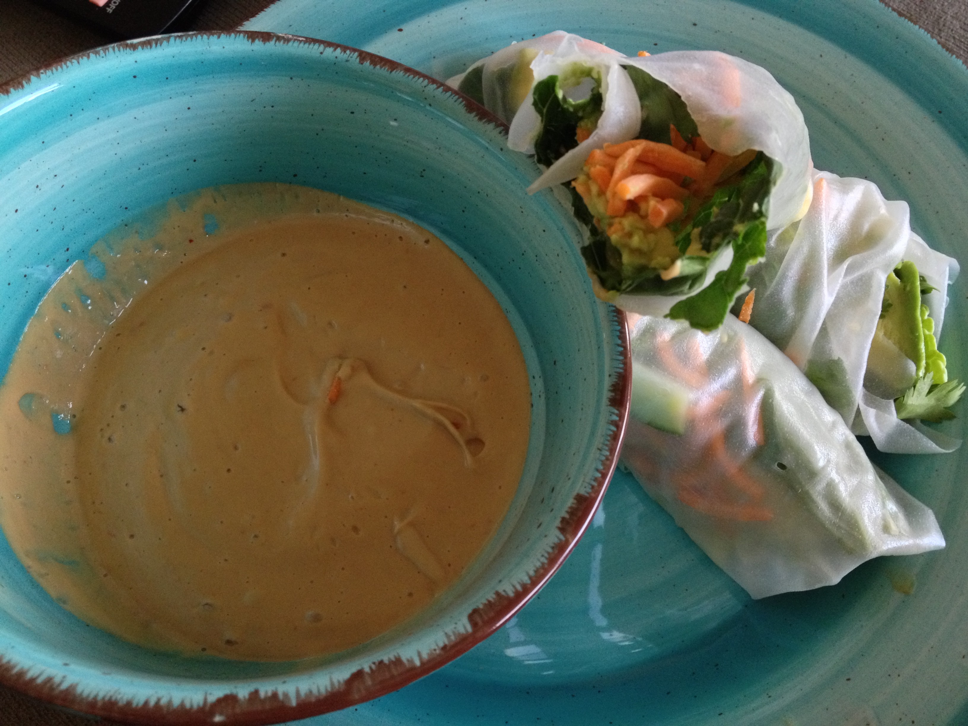 A bowl with peanut butter sauce and two fresh rolls