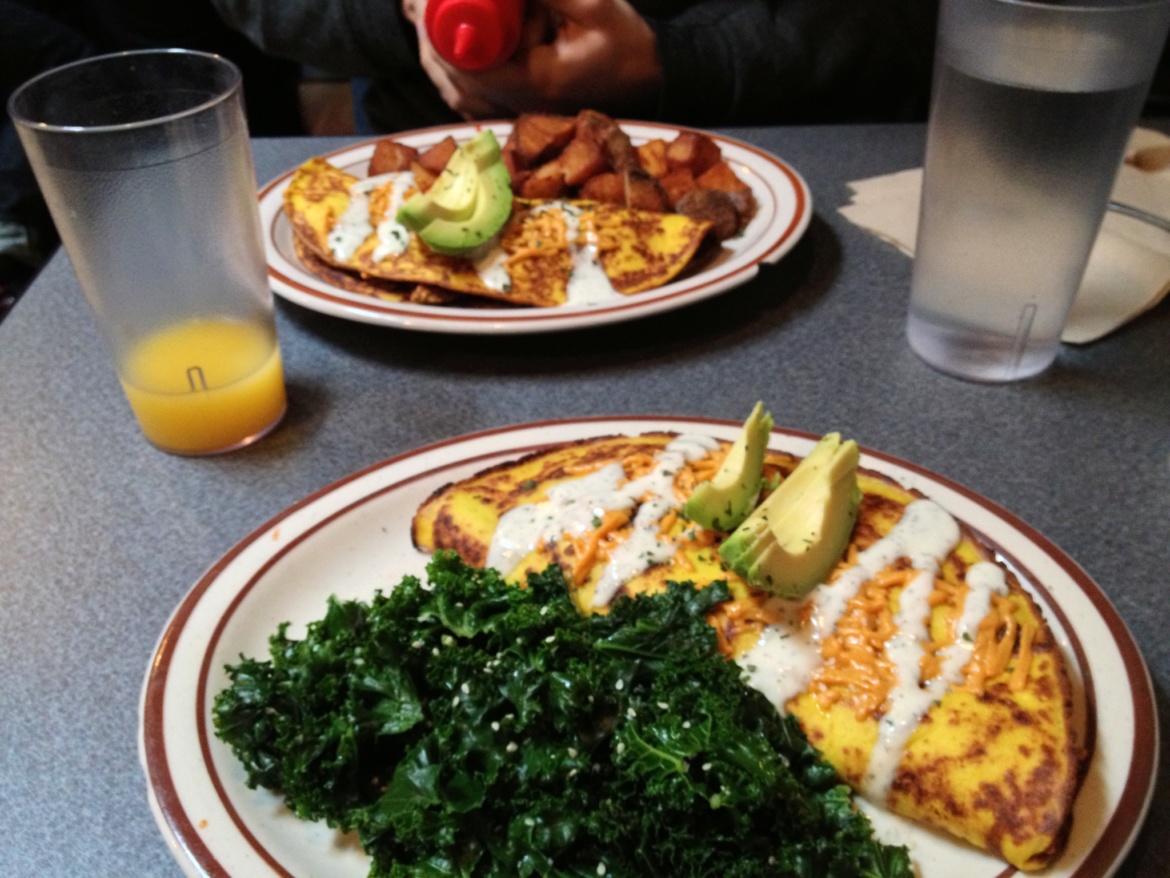 Two plates with omelet and kale on a kitchen table
