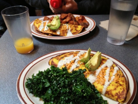 Two plates with omelet and kale on a kitchen table