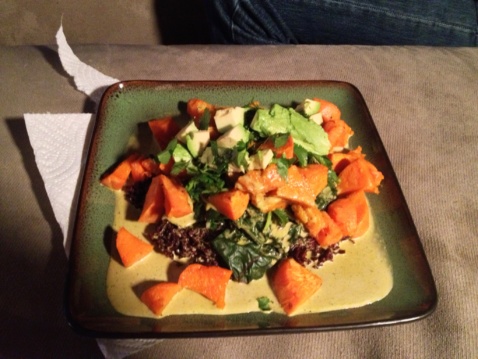 Gandhi Bowl with sweet potatoes, greens and sauce on a black square plate