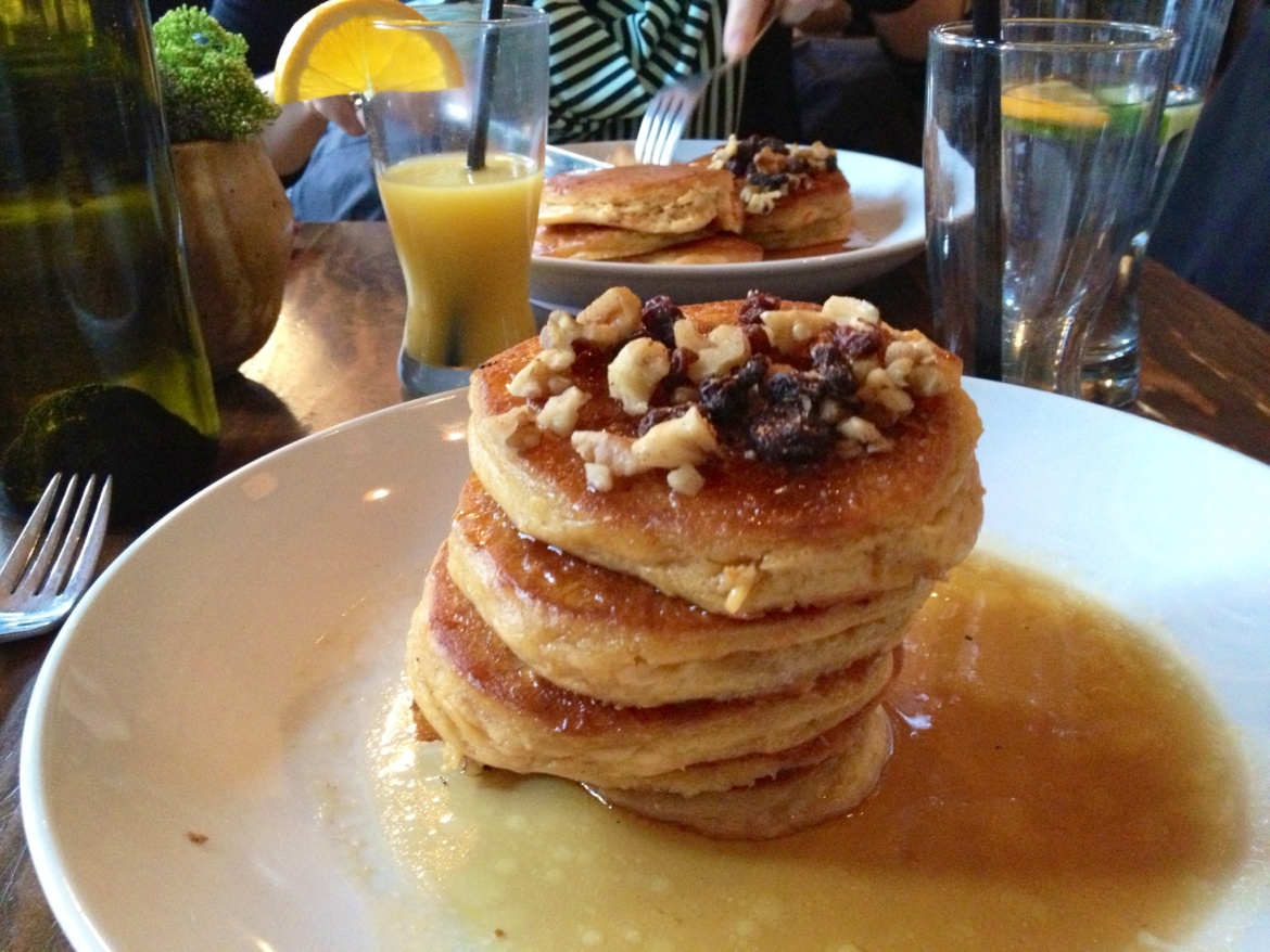 Pancakes with syrup and nuts on a white plate
