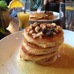 Pancakes with syrup and nuts on a white plate