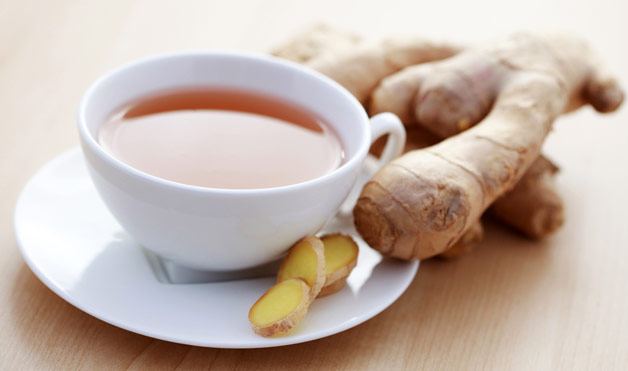 A cup of ginger tea and a ginger root next to it