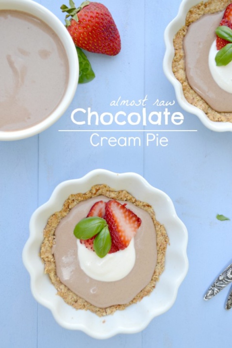 Two chocolate cream pies with strawberries on a light blue surface