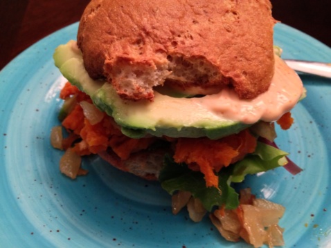 A sandwich with roasted sweet potato, caramelized onions and sriracha mayo on a light blue plate