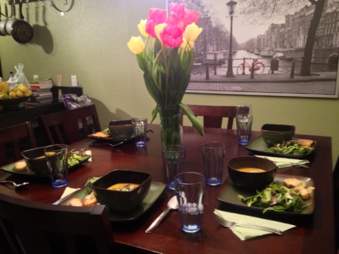 A dinner table setting with a centerpiece of yellow and purple tulips