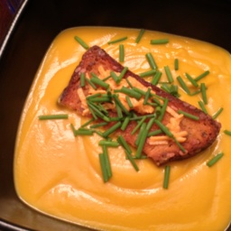 Creamy acorn squash soup with cheesy croutons in a black square bowl