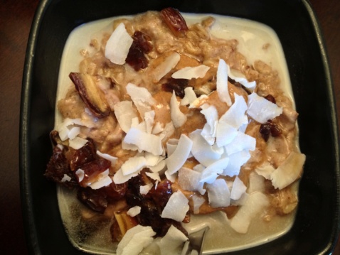 Gluten-free banana bread oatmeal with dates and coconut flakes in a black square bowl