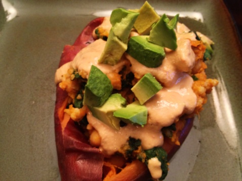Yam boats with chickpeas, chard and spicy cashew cream sauce on a square plate