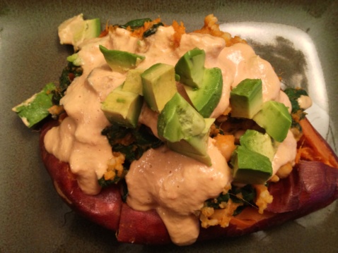 A close up of a baked sweet potato with chickpeas, chard and spicy cashew cream sauce