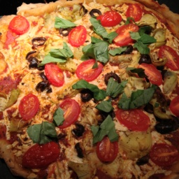 Pizza pie with cherry tomatoes, artichokes, olives, and basil