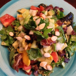Multi-nutrient salad with greens, seeds, fruits and vegetables on a light blue plate