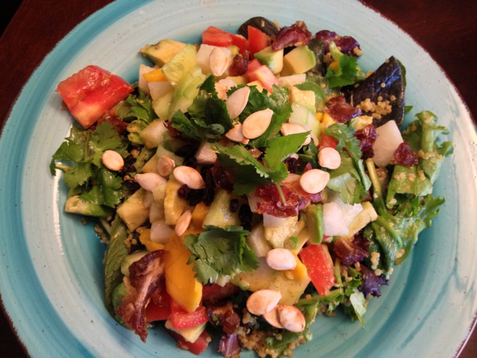 Multi-nutrient salad with greens, seeds, fruits and vegetables on a light blue plate
