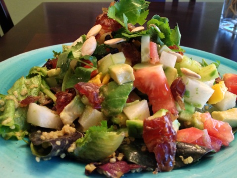 Multi-nutrient salad with quinoa, greens, seeds, fruits and vegetables on a light blue plate