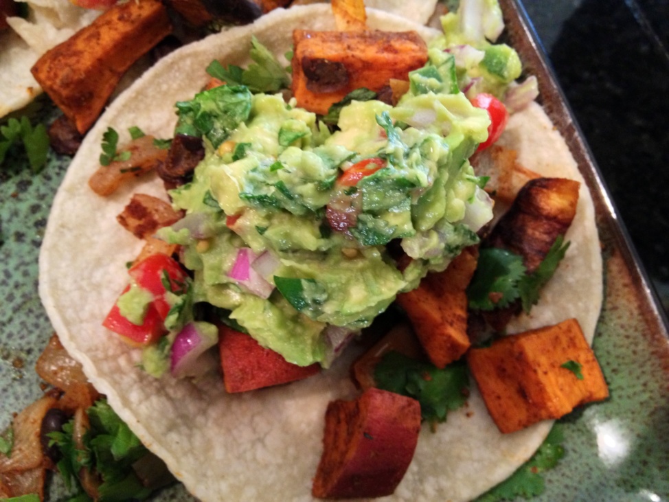 A Tortilla with roasted sweet potatoes and guacamole on it