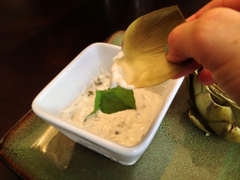 Lauren dipping an artichoke leaf in aioli