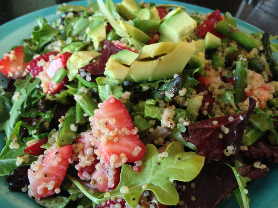 A green salad with quinoa, avocado, and strawberries