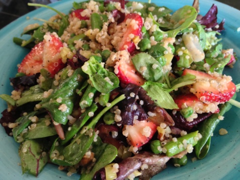 A green salad with quinoa, avocado, peas, and strawberries