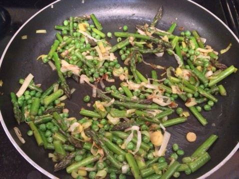 Peas, asparagus, garlic and leek cooking in a skillet