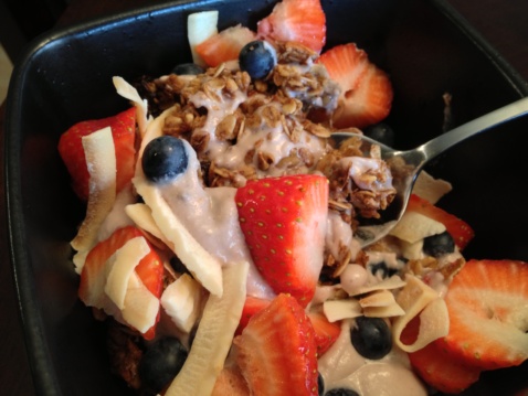 Coconut yogurt granola and strawberries in a black bowl