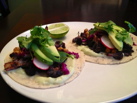 Two tacos with cauliflower, red cabbage, avocado, and chickpeas