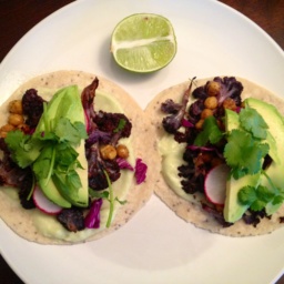 Two tacos with cauliflower, chickpeas, avocado, and cilantro on a plate