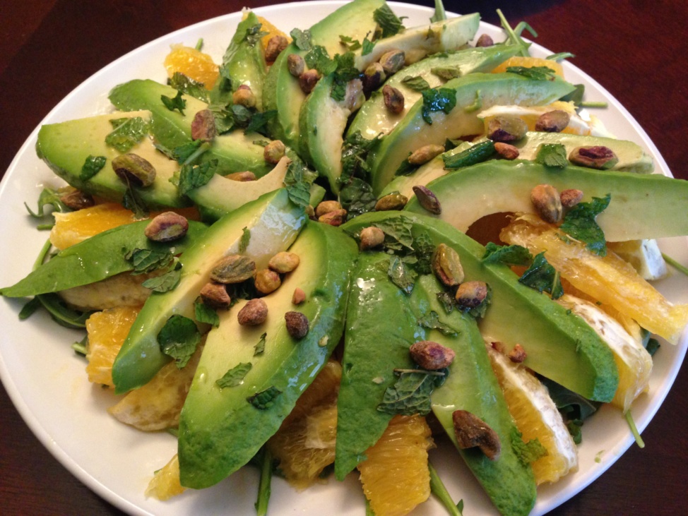 A salad of sliced avocado, oranges, and arugula