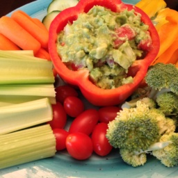 Guacamole and different vegetables on a light blue plate