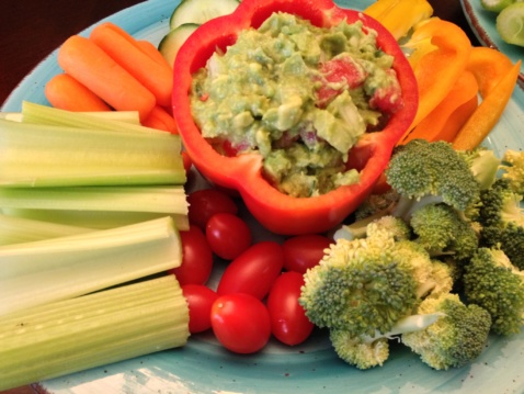 Guacamole and different vegetables on a light blue plate