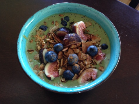 Green smoothie bowl with granola, figs and blueberries