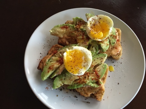 Avocado toast with soft boiled eggs on top, seasoned with salt, pepper and paprika