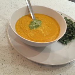 Roasted carrot soup with spring pesto in a white bowl