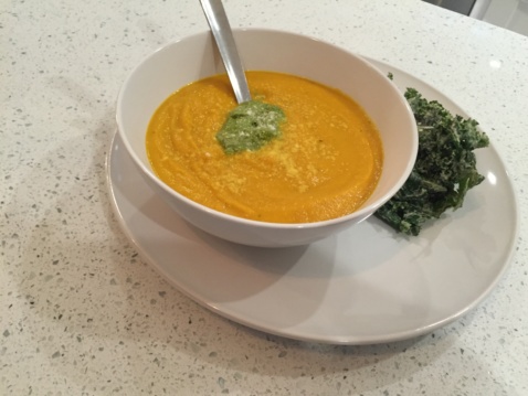 Roasted carrot soup with spring pesto in a white bowl