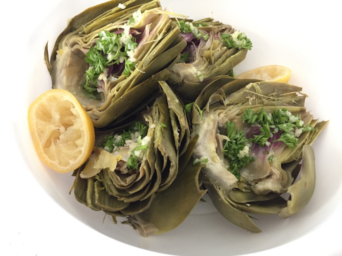 Grilled artichokes with olive oil dressing on a white plate