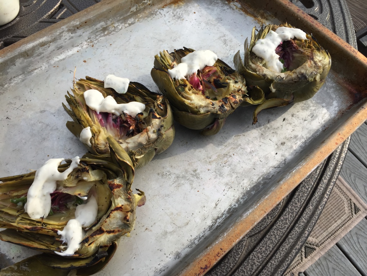 Grilled artichokes with aioli on a baking tray