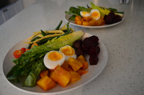 Two plates of Nicoise salad with romaine, beets, and boiled eggs