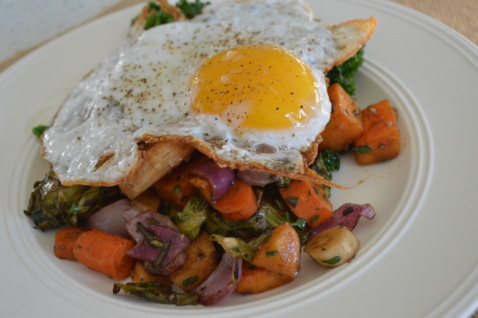 Sauteed vegetables with a fried egg on a white plate