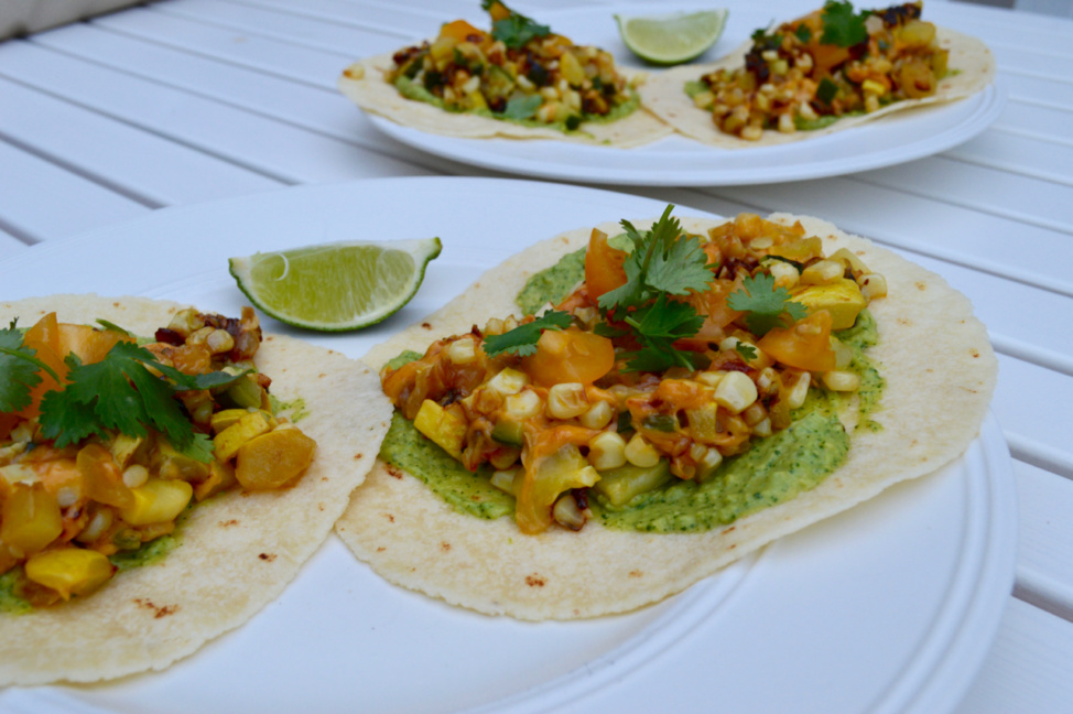 Two summer squash & corn tacos with avocado cilantro crema