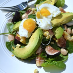 Summer salad with figs sweet corn and sun gold tomatoes on a white plate