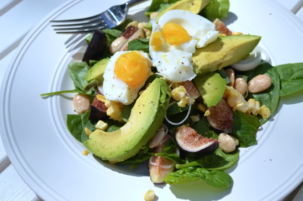 Summer salad with figs sweet corn and sun gold tomatoes on a white plate