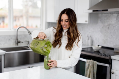 Lauren pouring a green smoothie in a mason jar