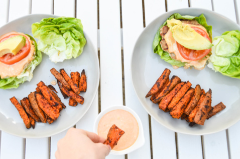Two plates with grilled turkey burgers and sweet potato fries